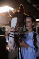 Female vet with eyes closed standing by horse at stable