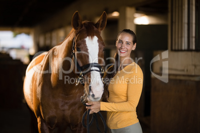 Portrait of smiling female jockey standing by horse