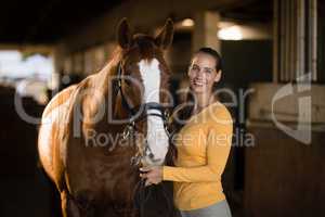 Portrait of smiling female jockey standing by horse