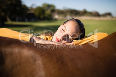 Female jockey relaxing on horse at barn