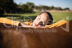 Female jockey relaxing on horse at barn