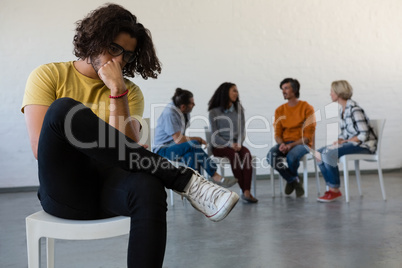 Man sitting on chair with friends discussing in background