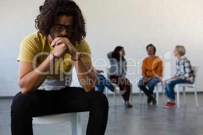 Adult student sitting on chair with friends discussing in background