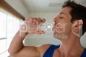 Close up of male athlete drinking water in gym