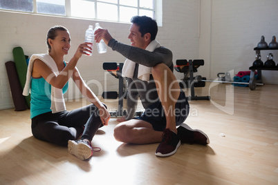 Trainer and athlete toasting water bottles while relaxing