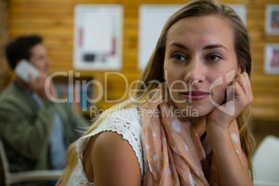 Thoughtful woman looking away while man talking on phone in background