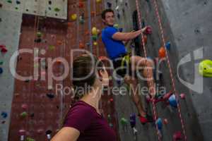 Athlete looking at trainer climbing wall at gym