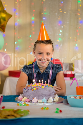 Girl standing with birthday cake at home