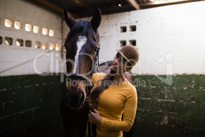 Female jockey looking at horse