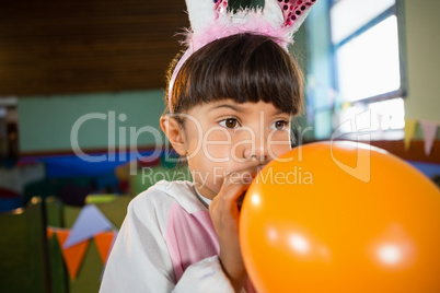 Adorable girl blowing balloon during birthday party