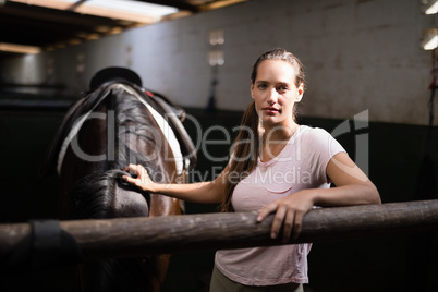 Portrait of young female jockey standing by horse