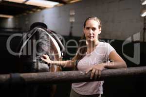 Portrait of young female jockey standing by horse