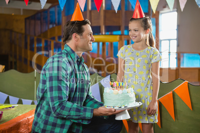 Father giving surprised birthday cake to her daughter