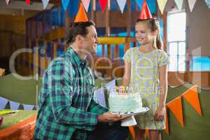 Father giving surprised birthday cake to her daughter