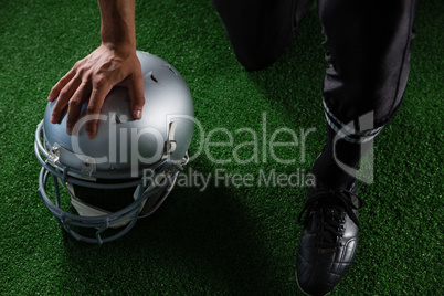 American football player resting his hands on head gear