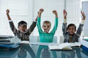 Cheerful business people with arms raised sitting in boardroom