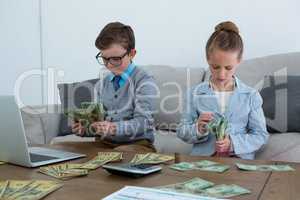 Colleagues counting currency while sitting on sofa