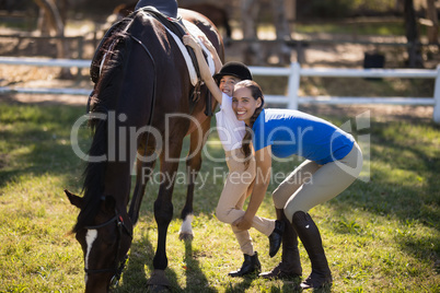 Portrait of female jockey assisting girl
