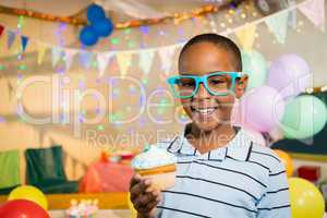 Portrait of cute boy holding cupcake during birthday party