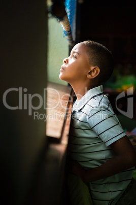 Thoughtful boy looking through window