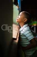 Thoughtful boy looking through window