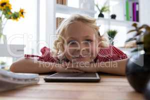 Portrait of happy businesswoman with tablet computer relaxing on table in office