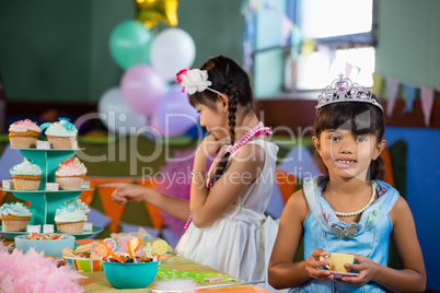 Cute girl having tea at table during birthday party