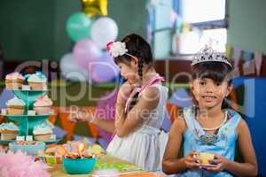 Cute girl having tea at table during birthday party