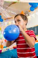 Cute boy blowing balloon during birthday party