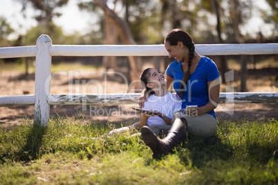 Smiling siblings talking while holding technologies