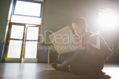 Boy sitting on wooden floor using laptop