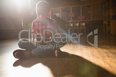 Boy sitting on wooden floor using digital tablet