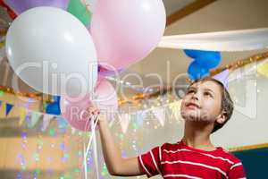 Cute boy holding colorful balloons during birthday party