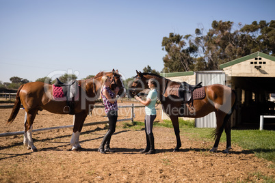 Side view of female friends with horse standing on field