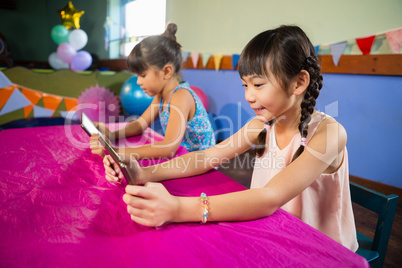 Little girls using tablet at party