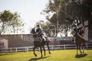 Friends riding horse at equestrian center