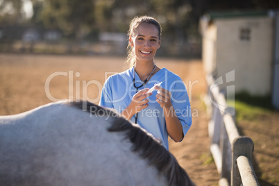 Portrait of smiling female vet holding syringe