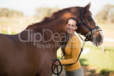Female jockey standing by horse at barn