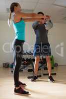 Male trainer training woman in lifting kettlebells
