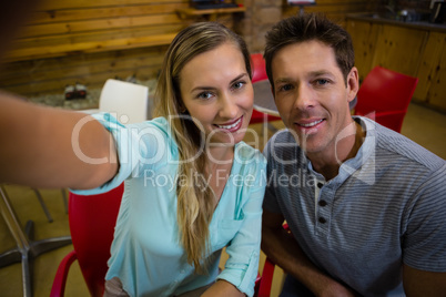 Portrait of happy couple sitting on chairs at cafe
