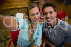 Portrait of happy couple sitting on chairs at cafe