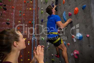 Female athlete cheering trainer climbing wall