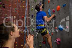 Female athlete cheering trainer climbing wall