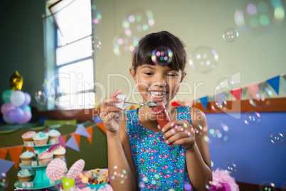 Adorable girl blowing balloon during birthday party