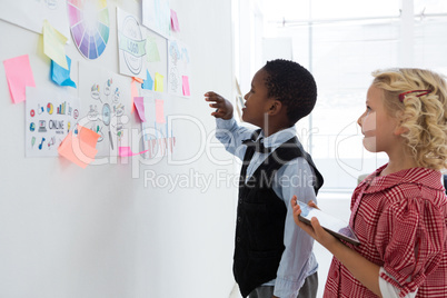 Businessman explaining to female colleague at whiteboard in office