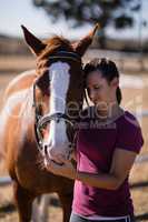 Female jockey with eyes closed standing by horse