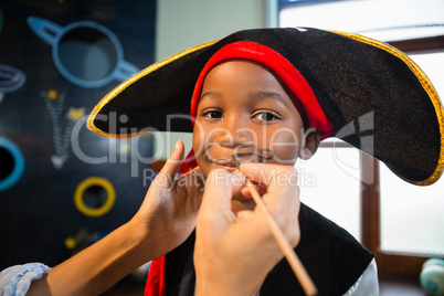 Hand of woman drawing mustache on boy face