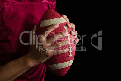 American football player holding a football with both his hands