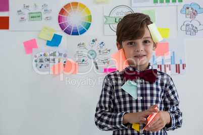 Portrait of cute businessman with sticky notes standing against whiteboard in office