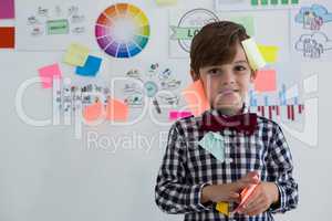 Portrait of cute businessman with sticky notes standing against whiteboard in office